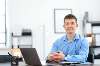 Photo of Portrait of handsome man at desk in office. Space for text