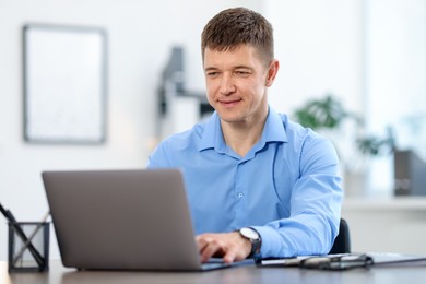 Photo of Man working on laptop at desk in office