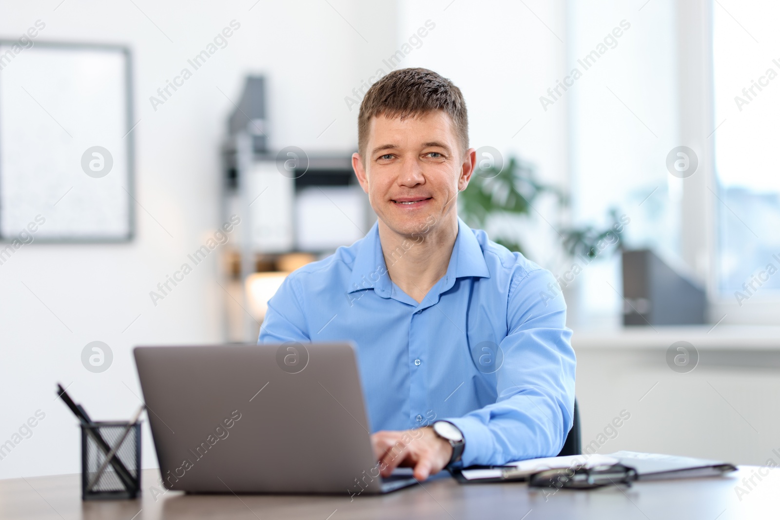 Man working on laptop at desk in office Photo of Man working on laptop at desk in office