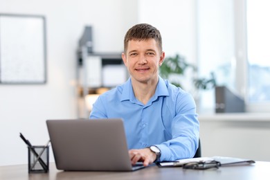 Photo of Man working on laptop at desk in office