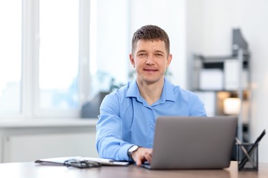 Photo of Man working on laptop at desk in office. Space for text
