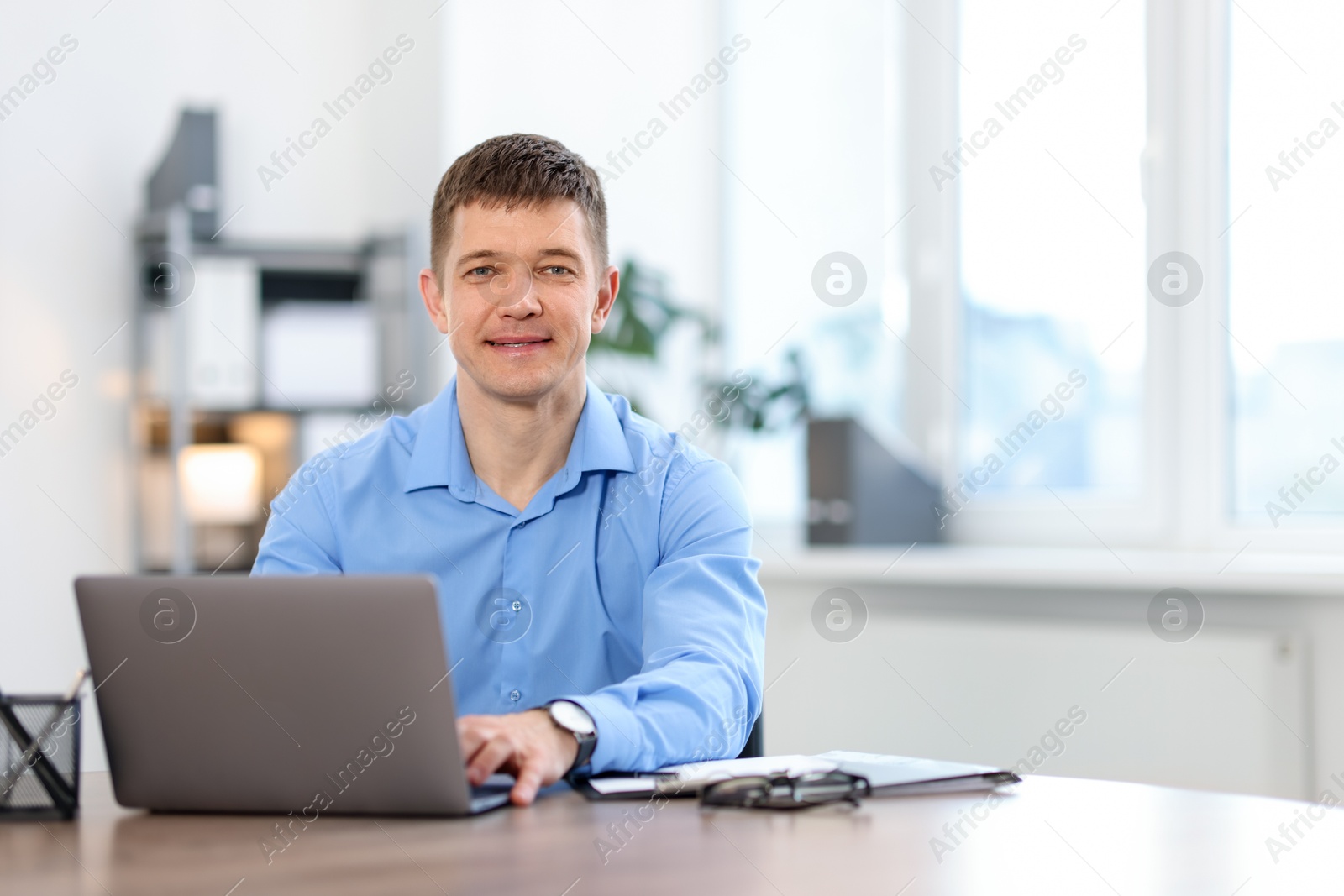 Man working on laptop at desk in office. Space for text Photo of Man working on laptop at desk in office. Space for text