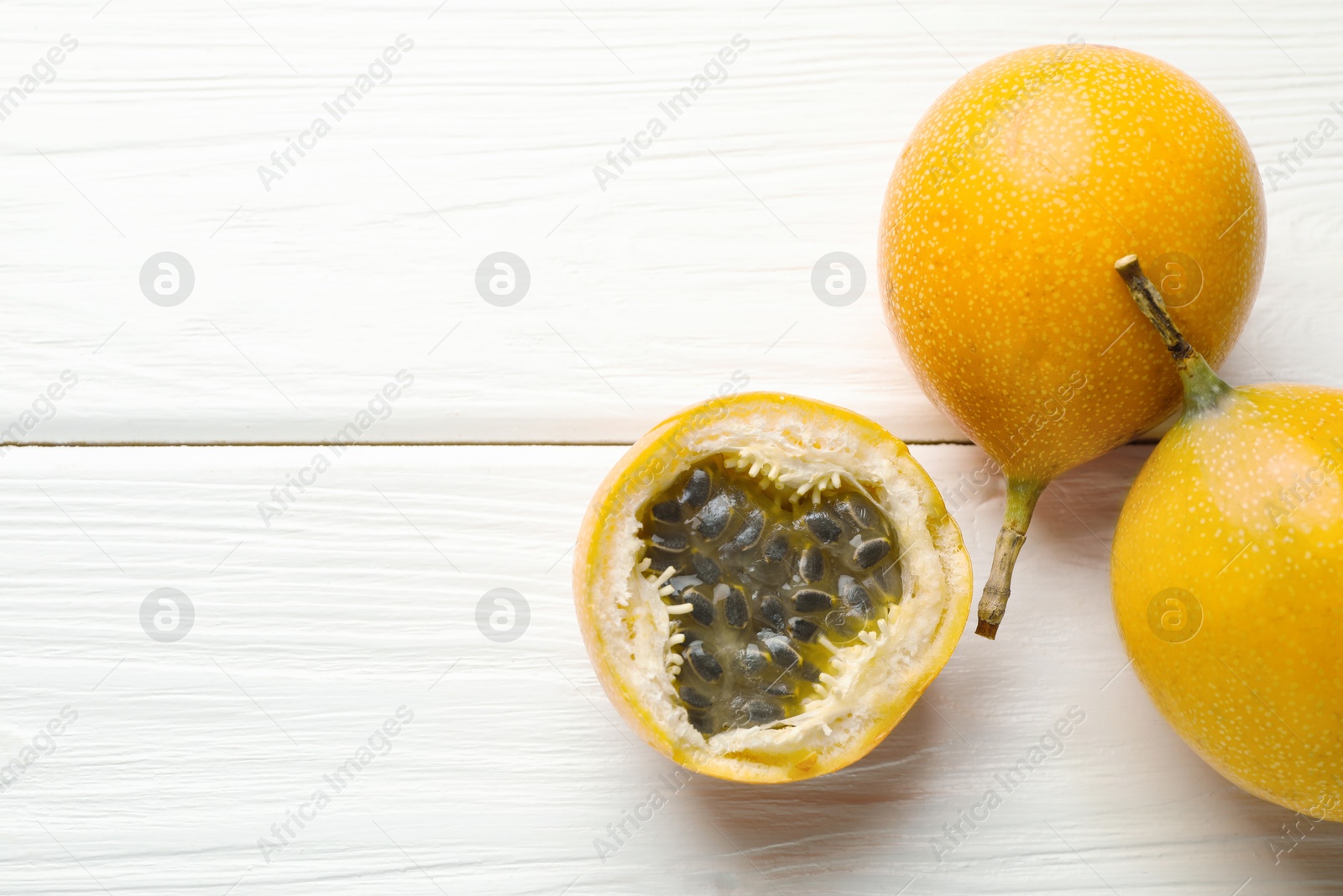 Ripe passion fruits on white wooden table, flat lay. Space for text Photo of Ripe passion fruits on white wooden table, flat lay. Space for text