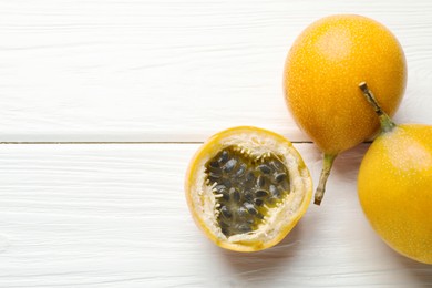 Photo of Ripe passion fruits on white wooden table, flat lay. Space for text