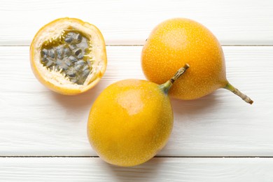 Photo of Ripe passion fruits on white wooden table, flat lay