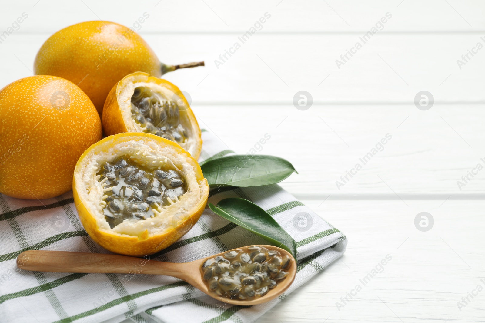 Ripe passion fruits, green leaves and seeds on white wooden table, closeup. Space for text Photo of Ripe passion fruits, green leaves and seeds on white wooden table, closeup. Space for text