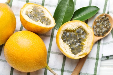 Photo of Ripe passion fruits, green leaves and seeds on table, flat lay