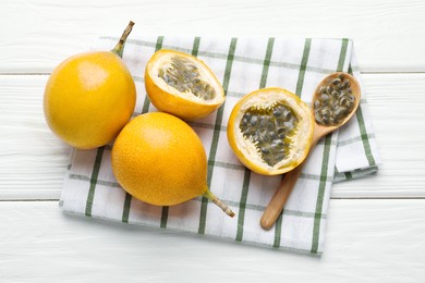 Photo of Ripe passion fruits and seeds on white wooden table, flat lay