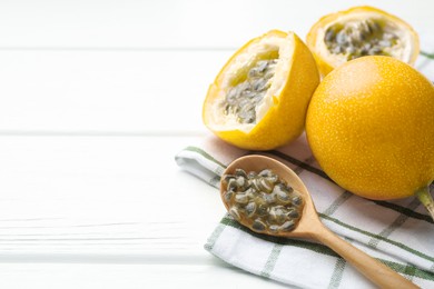 Photo of Ripe passion fruits and seeds on white wooden table, closeup. Space for text