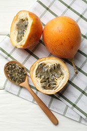 Photo of Ripe passion fruits and seeds on white wooden table, flat lay