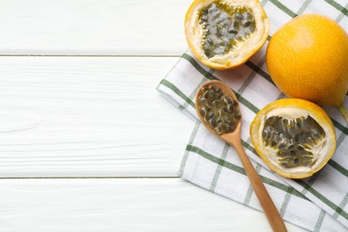 Photo of Ripe passion fruits and seeds on white wooden table, flat lay. Space for text