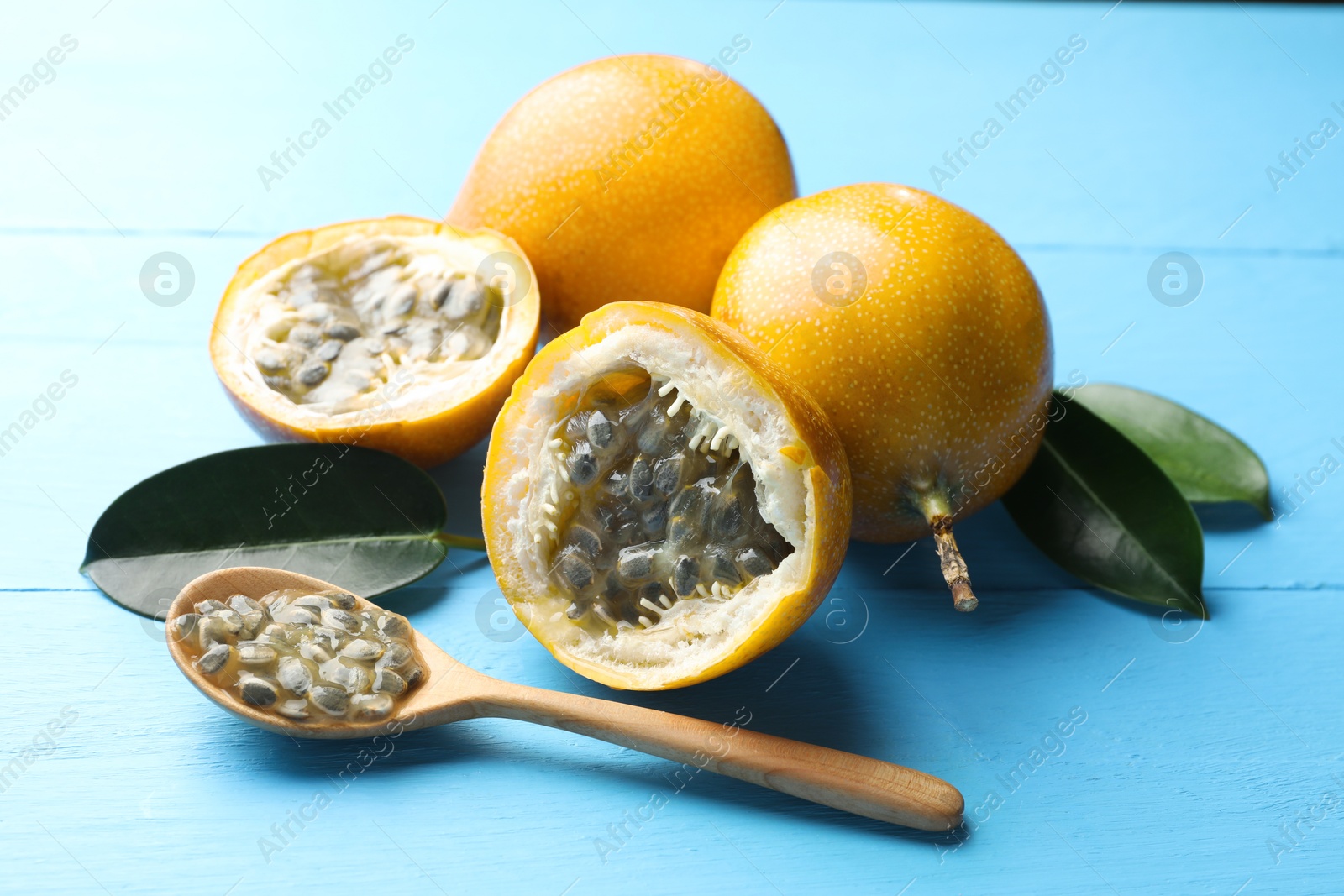 Ripe passion fruits, green leaves and seeds on light blue wooden table, closeup Photo of Ripe passion fruits, green leaves and seeds on light blue wooden table, closeup