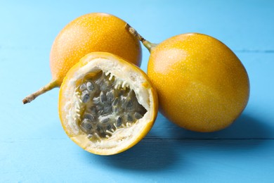 Photo of Ripe passion fruits on light blue wooden table, closeup