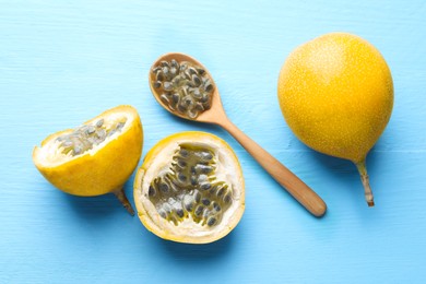 Photo of Ripe passion fruits and seeds on light blue wooden table, flat lay