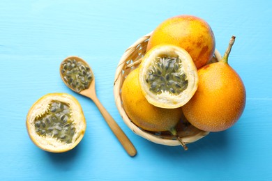 Photo of Ripe passion fruits and seeds on light blue wooden table, flat lay