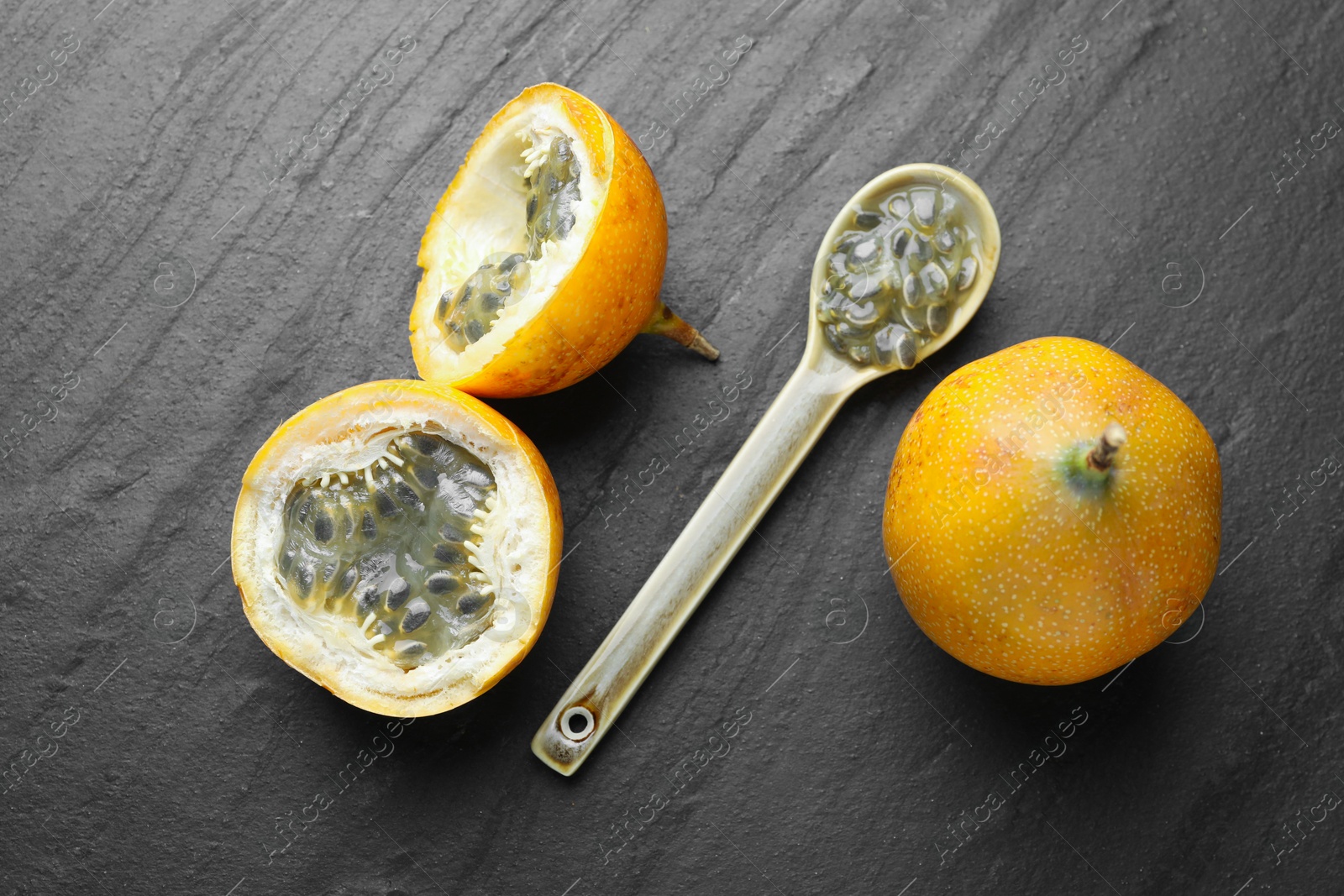 Ripe passion fruits and seeds on black table, flat lay Photo of Ripe passion fruits and seeds on black table, flat lay
