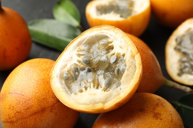 Photo of Ripe passion fruits and green leaves on table, closeup