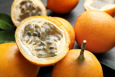 Photo of Ripe passion fruits and green leaves on table, closeup