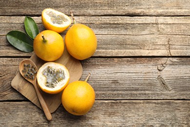 Photo of Ripe passion fruits, seeds and leaves on wooden table, flat lay. Space for text