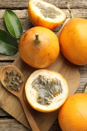 Photo of Ripe passion fruits, seeds and green leaves on wooden table, flat lay