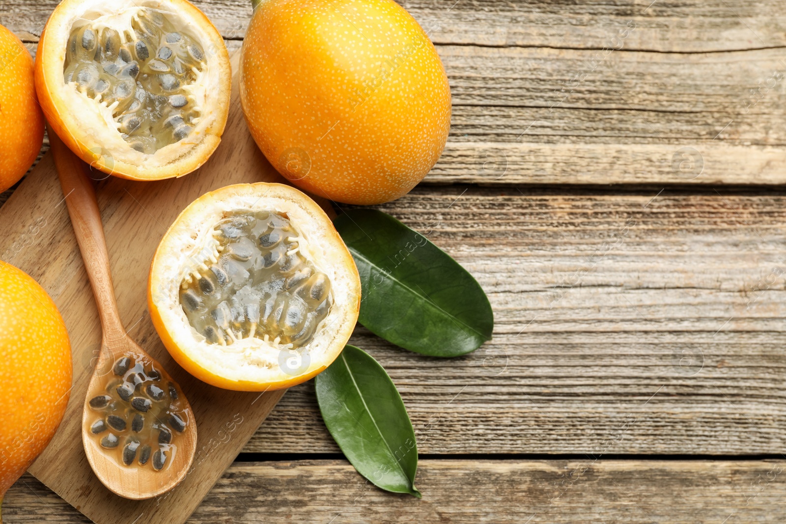 Ripe passion fruits, seeds and leaves on wooden table, flat lay. Space for text Photo of Ripe passion fruits, seeds and leaves on wooden table, flat lay. Space for text