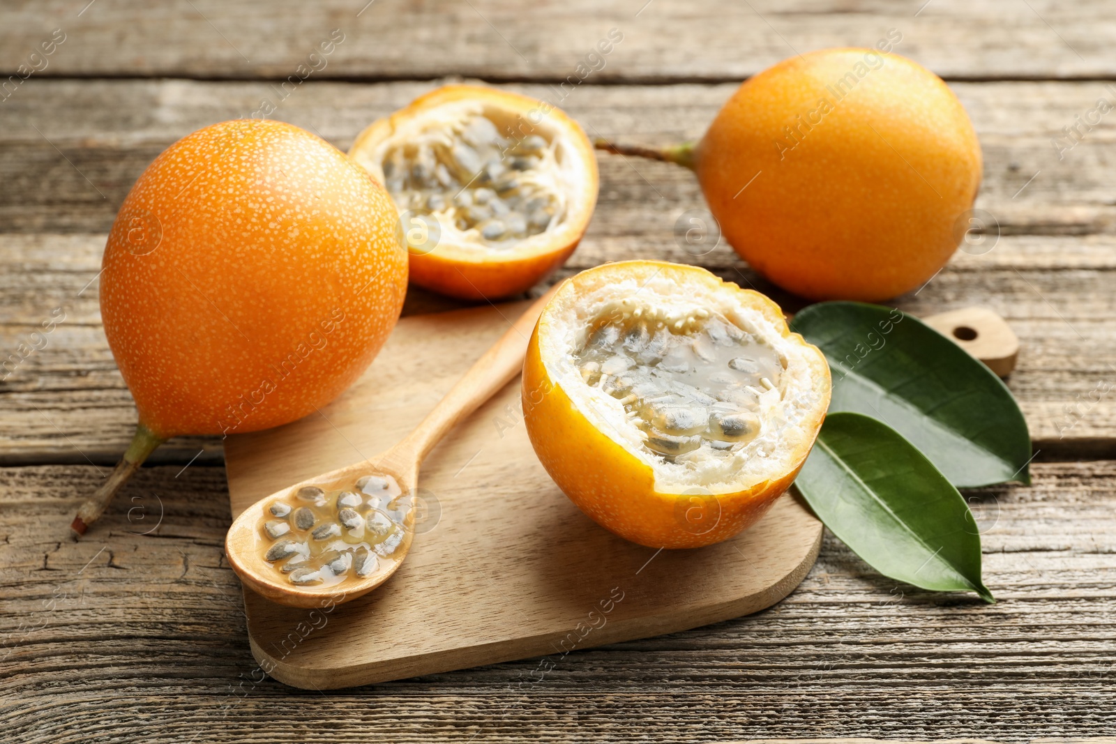 Ripe passion fruits, seeds and green leaves on wooden table, closeup Photo of Ripe passion fruits, seeds and green leaves on wooden table, closeup