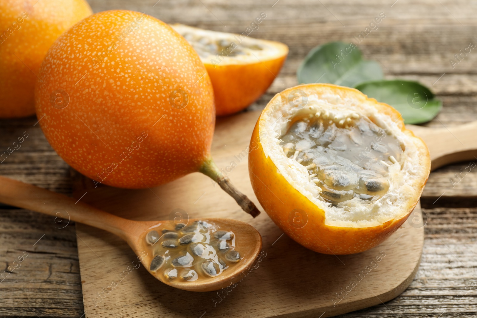 Ripe passion fruits, seeds and green leaves on wooden table, closeup Photo of Ripe passion fruits, seeds and green leaves on wooden table, closeup