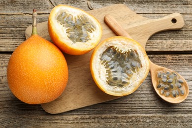 Photo of Ripe passion fruits and seeds on wooden table, flat lay