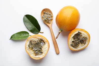 Photo of Ripe passion fruits, seeds and green leaves on white background, flat lay