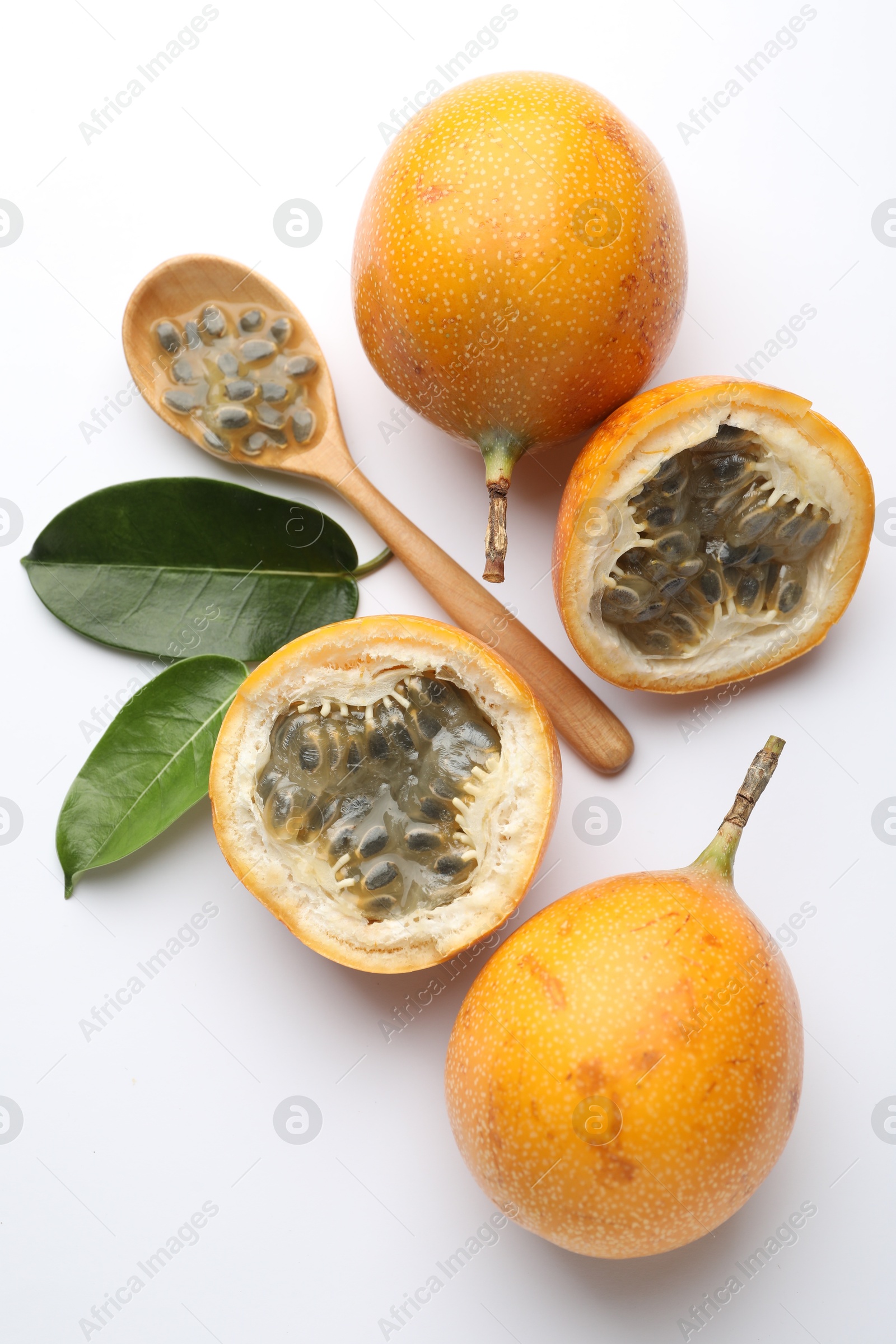 Ripe passion fruits, seeds and green leaves on white background, flat lay Photo of Ripe passion fruits, seeds and green leaves on white background, flat lay