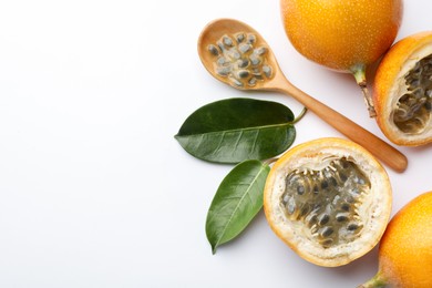 Photo of Ripe passion fruits, seeds and leaves on white background, flat lay. Space for text