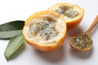 Photo of Ripe passion fruit, seeds and green leaves on white background, closeup