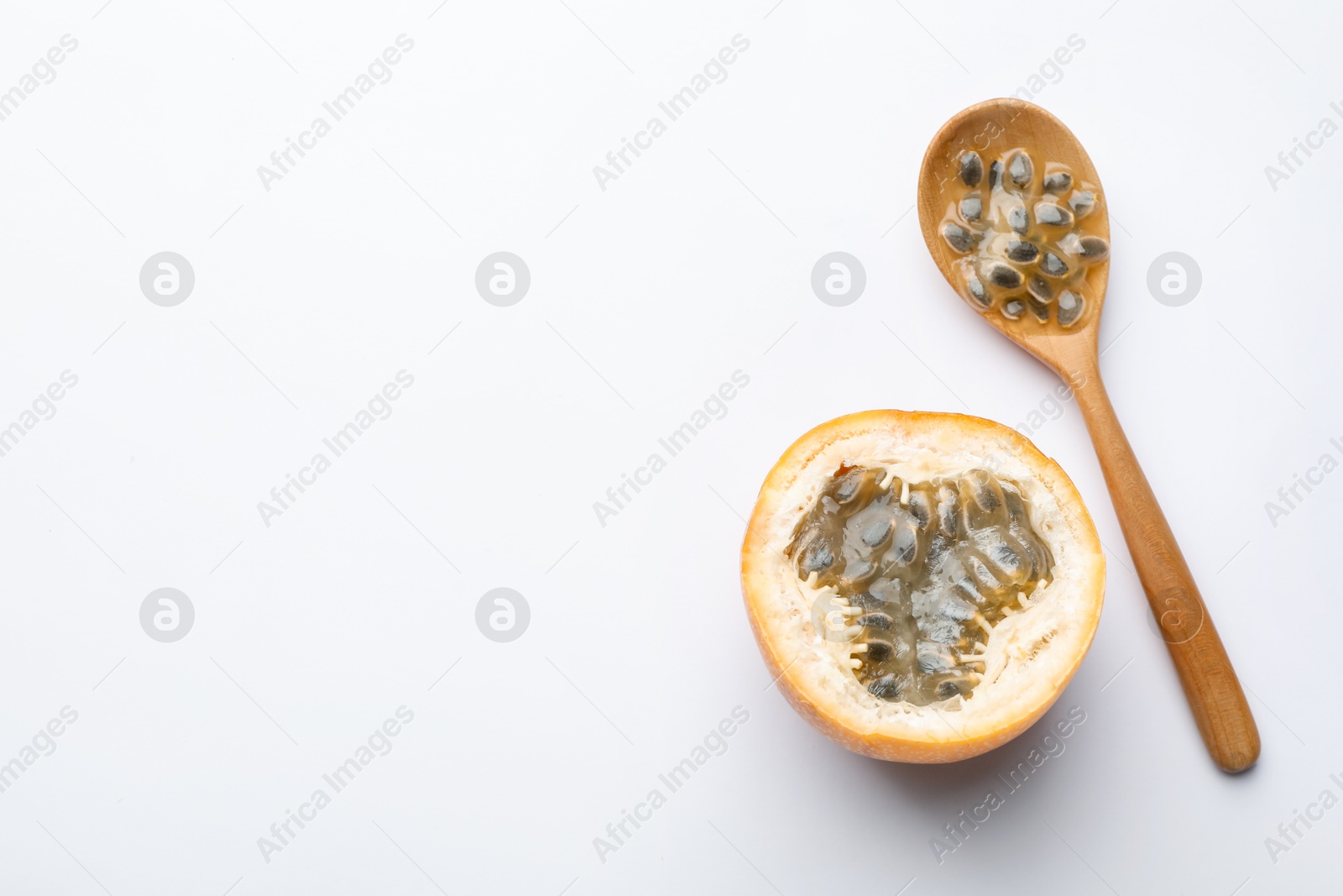 Ripe passion fruit, seeds and spoon on white background, flat lay. Space for text Photo of Ripe passion fruit, seeds and spoon on white background, flat lay. Space for text