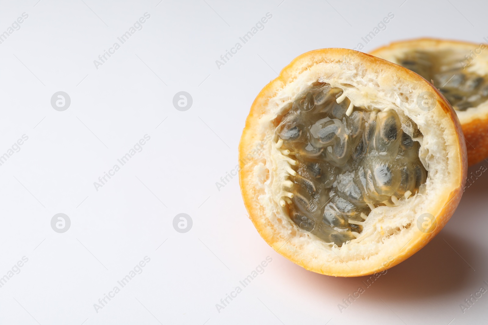 Halves of ripe passion fruit on white background, closeup. Space for text Photo of Halves of ripe passion fruit on white background, closeup. Space for text