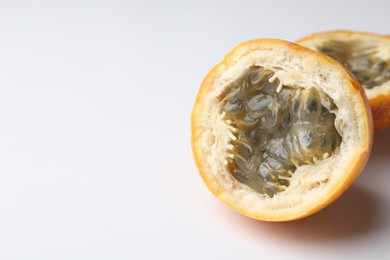 Photo of Halves of ripe passion fruit on white background, closeup. Space for text