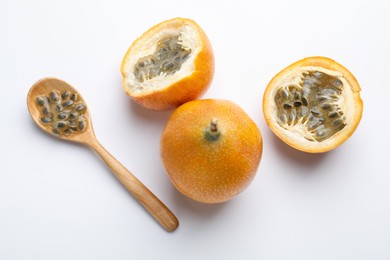 Photo of Ripe passion fruits, seeds and spoon on white background, flat lay