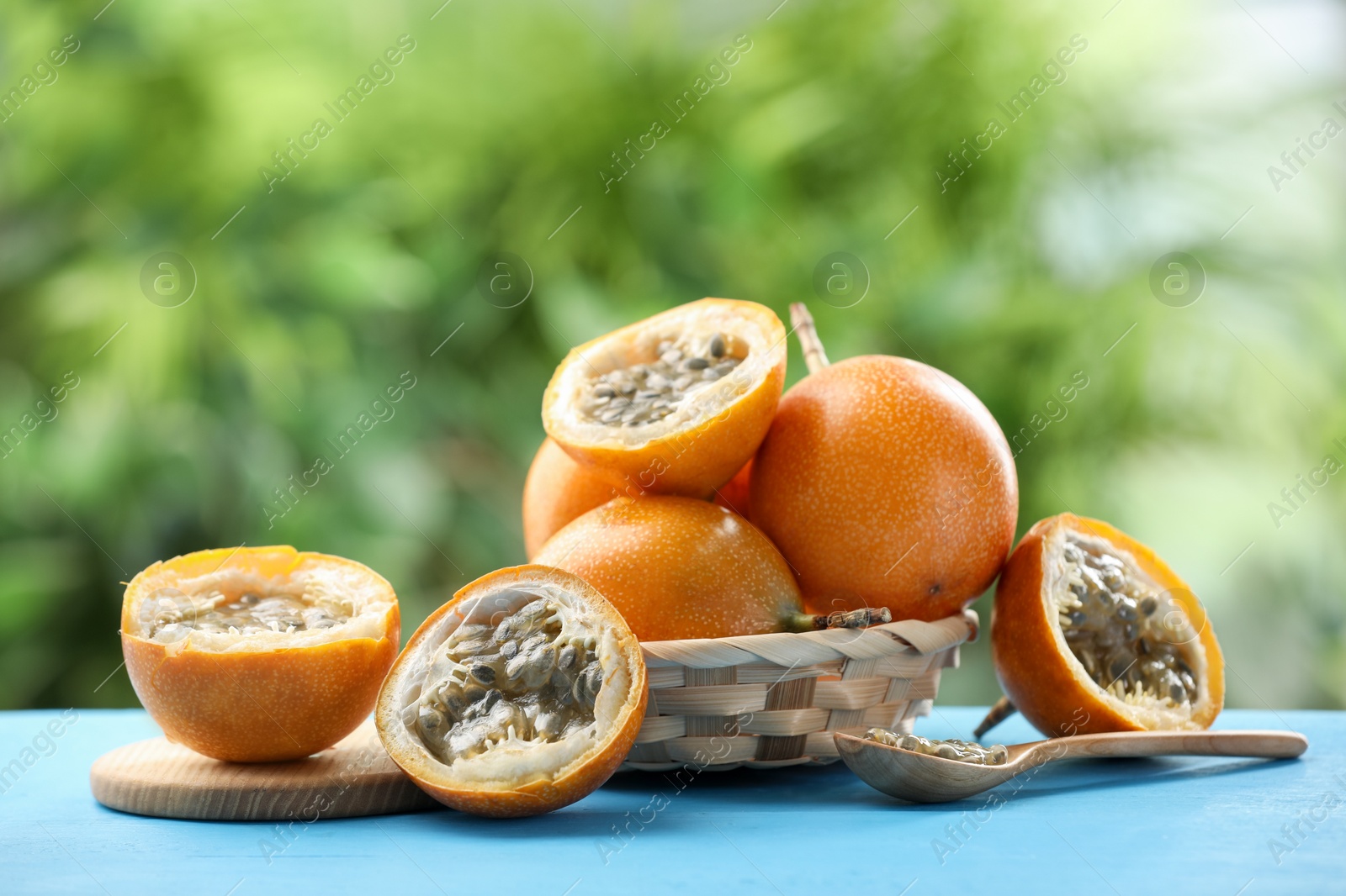 Ripe passion fruits and seeds on light blue wooden table outdoors Photo of Ripe passion fruits and seeds on light blue wooden table outdoors