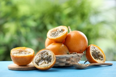 Photo of Ripe passion fruits and seeds on light blue wooden table outdoors
