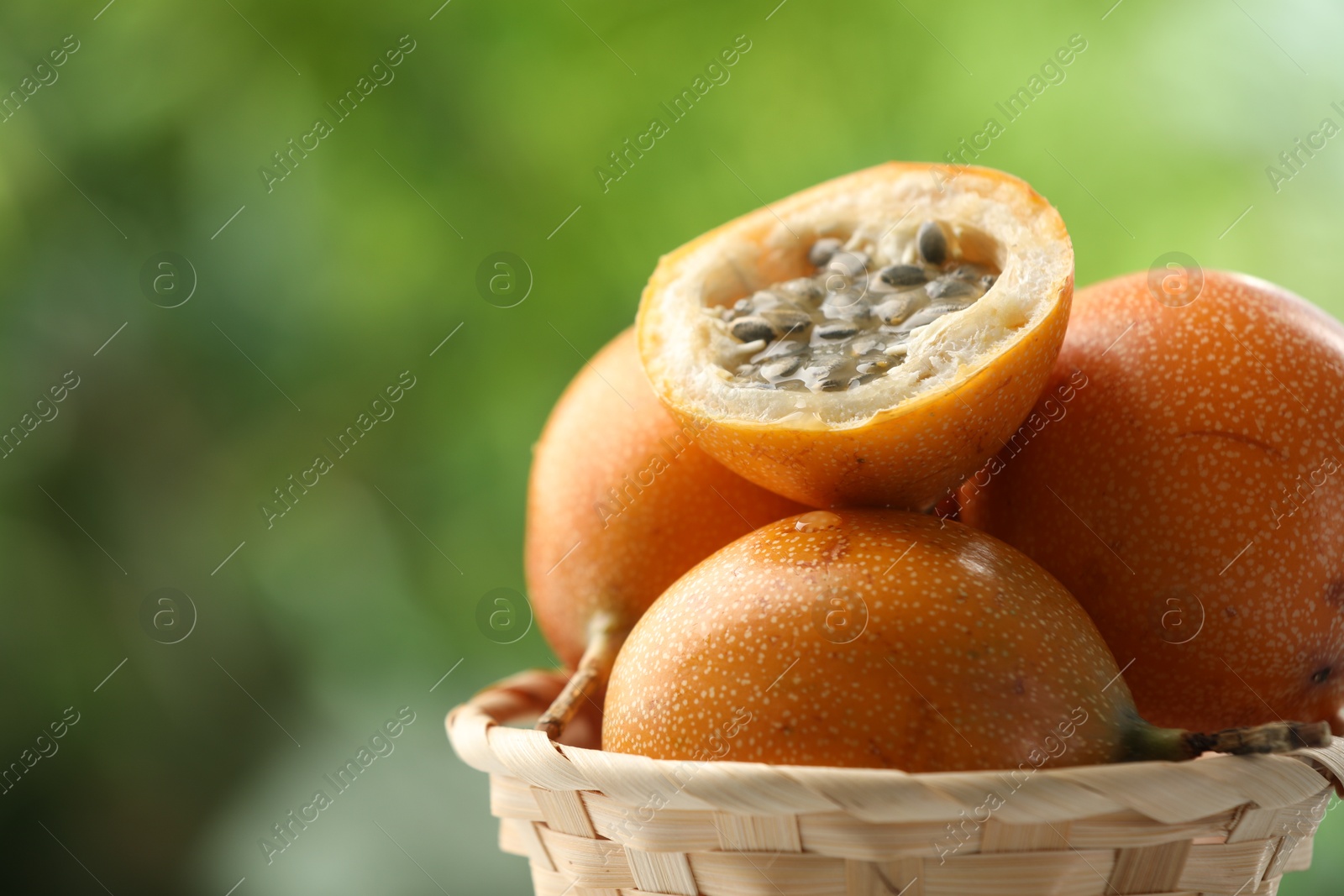 Ripe passion fruits in wicker basket outdoors, closeup. Space for text Photo of Ripe passion fruits in wicker basket outdoors, closeup. Space for text