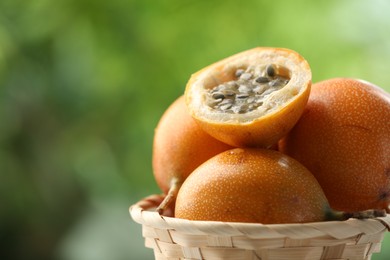Photo of Ripe passion fruits in wicker basket outdoors, closeup. Space for text
