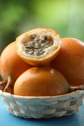 Photo of Ripe passion fruits in wicker basket on table outdoors, closeup