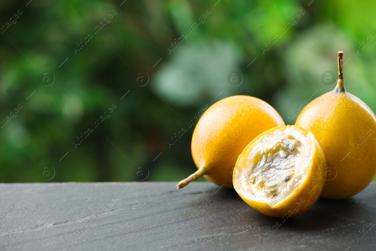 Ripe passion fruits on black table outdoors, closeup. Space for text Photo of Ripe passion fruits on black table outdoors, closeup. Space for text