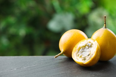 Photo of Ripe passion fruits on black table outdoors, closeup. Space for text