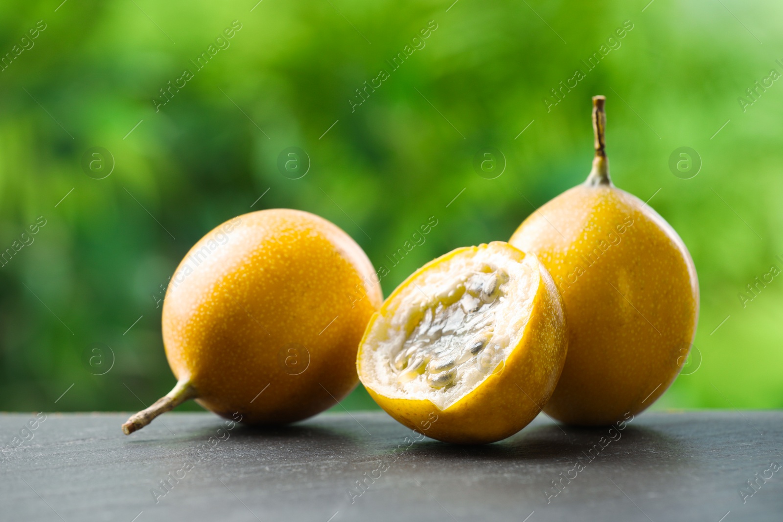 Photo of Ripe passion fruits on black table outdoors, closeup