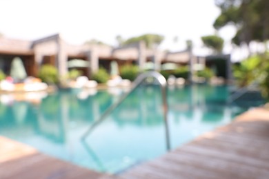 Photo of Outdoor swimming pool with wooden deck, blurred view. Luxury resort