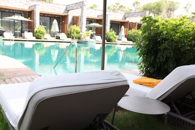 Photo of Sunbeds near outdoor swimming pool at luxury resort