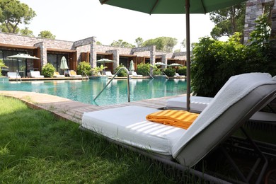 Photo of Sunbeds near outdoor swimming pool at luxury resort