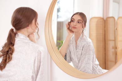 Photo of Beautiful woman looking at herself in mirror indoors