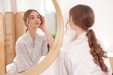 Photo of Beautiful woman looking at herself in mirror indoors