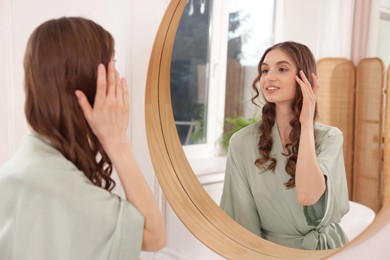 Photo of Beautiful woman looking at herself in mirror indoors